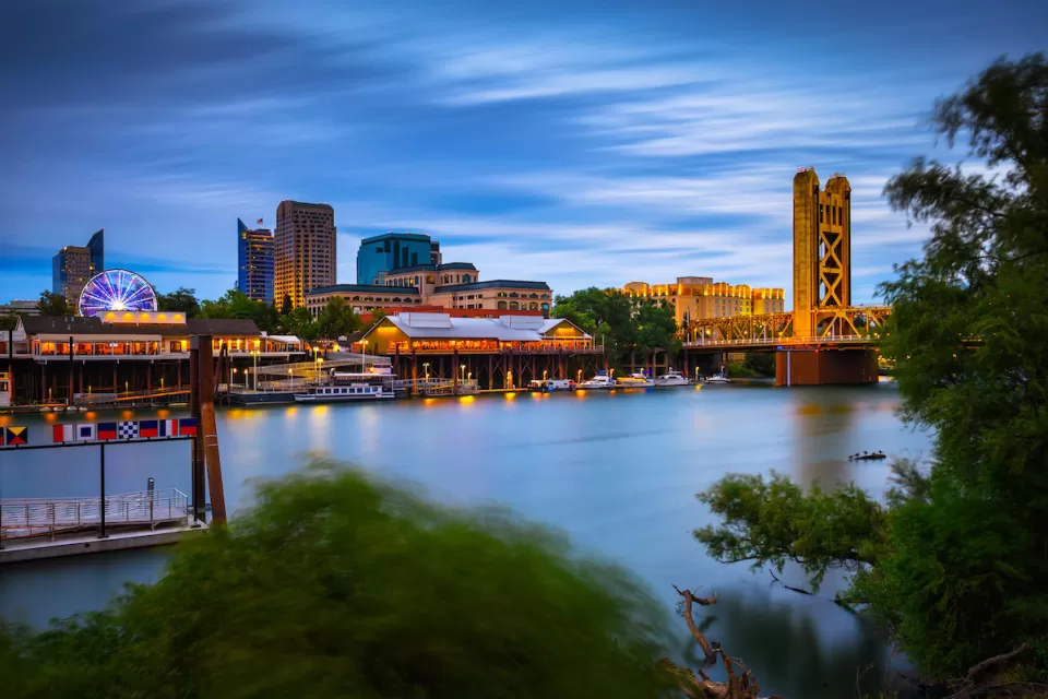Nighttime view of Sacramento River with Tower Bridge and Sacramento skyline.